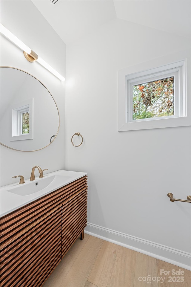 bathroom featuring vanity, wood-type flooring, and vaulted ceiling