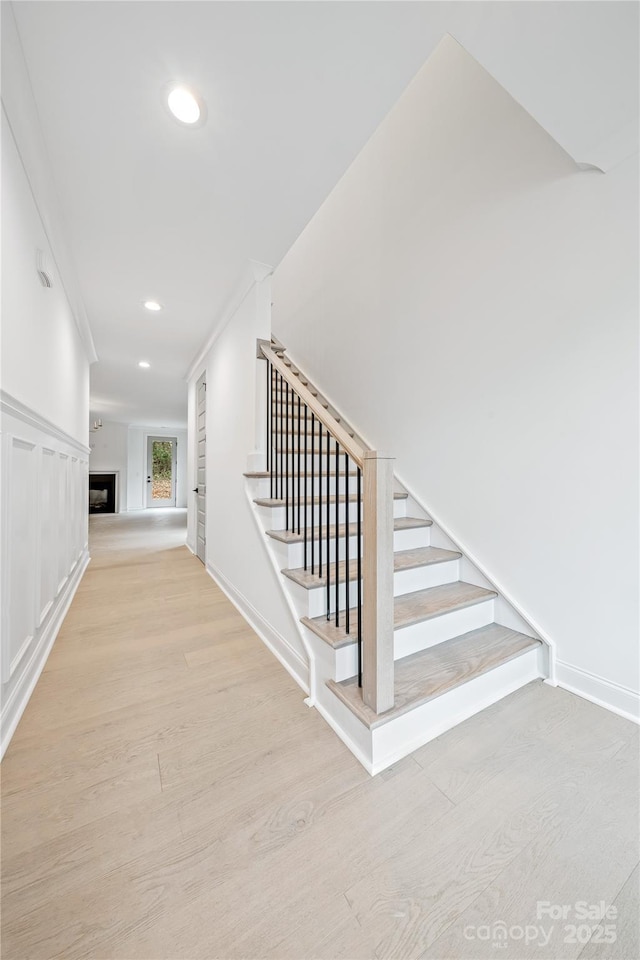 staircase featuring wood-type flooring and crown molding