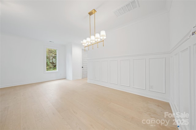 spare room with light hardwood / wood-style flooring and a chandelier