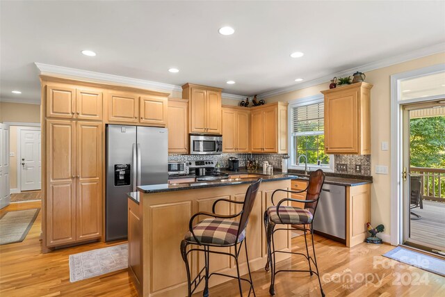 kitchen featuring backsplash, stainless steel appliances, light hardwood / wood-style floors, and crown molding