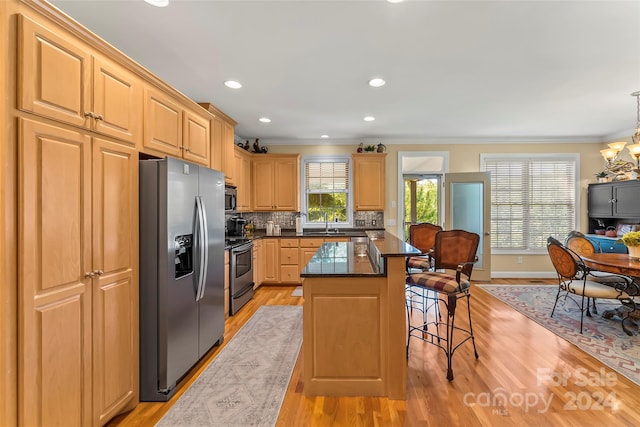 kitchen featuring a center island, sink, appliances with stainless steel finishes, light hardwood / wood-style flooring, and tasteful backsplash