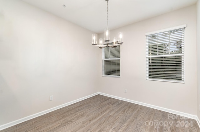 empty room with a chandelier and hardwood / wood-style floors