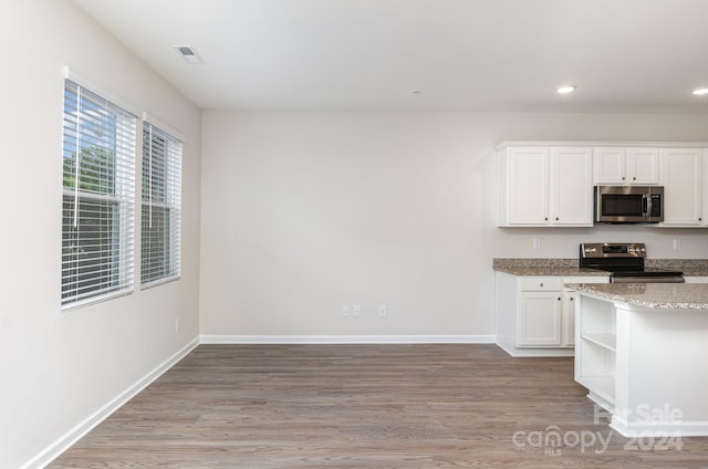 kitchen with white cabinets, light stone countertops, stainless steel appliances, and light wood-type flooring