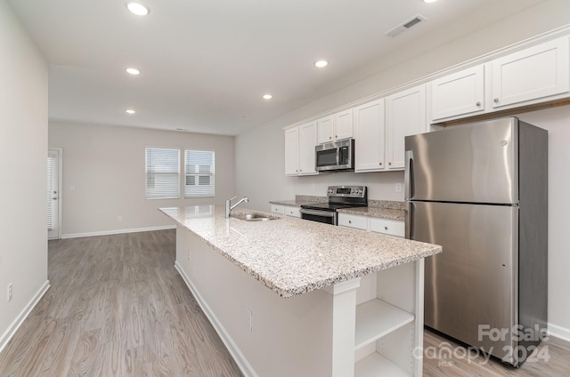 kitchen featuring sink, light hardwood / wood-style floors, stainless steel appliances, white cabinets, and a center island with sink