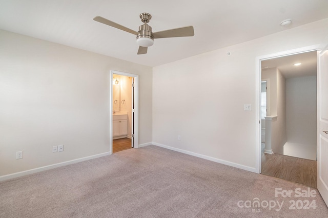 unfurnished bedroom featuring connected bathroom, ceiling fan, and light colored carpet