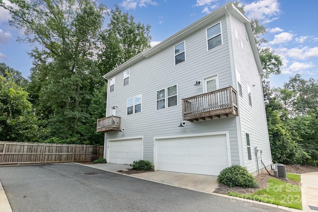 rear view of house featuring a balcony, a garage, and central air condition unit