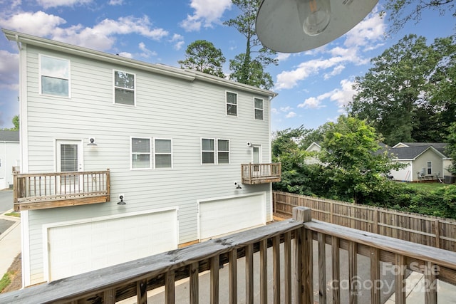 rear view of house with a balcony, a wooden deck, and a garage