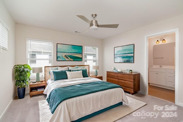 carpeted bedroom with ensuite bathroom, sink, and ceiling fan