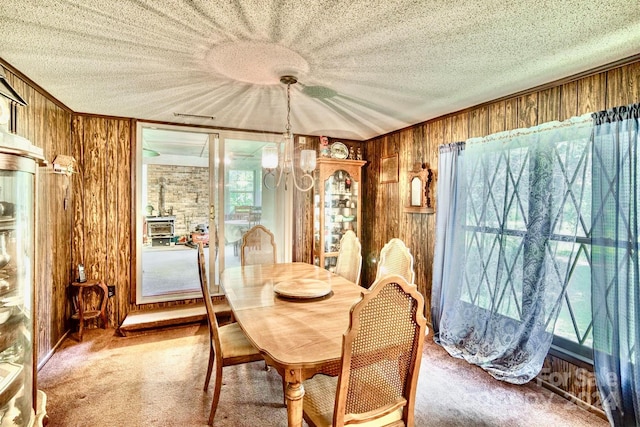 carpeted dining room with wood walls and a textured ceiling