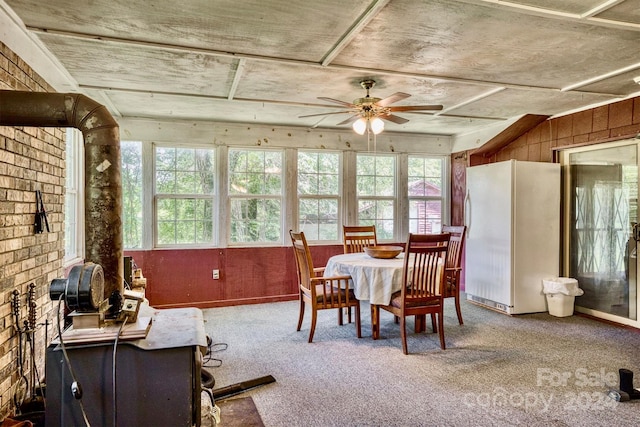 dining room featuring ceiling fan, wooden walls, and carpet floors