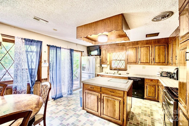 kitchen featuring a textured ceiling, sink, stainless steel appliances, and tile counters