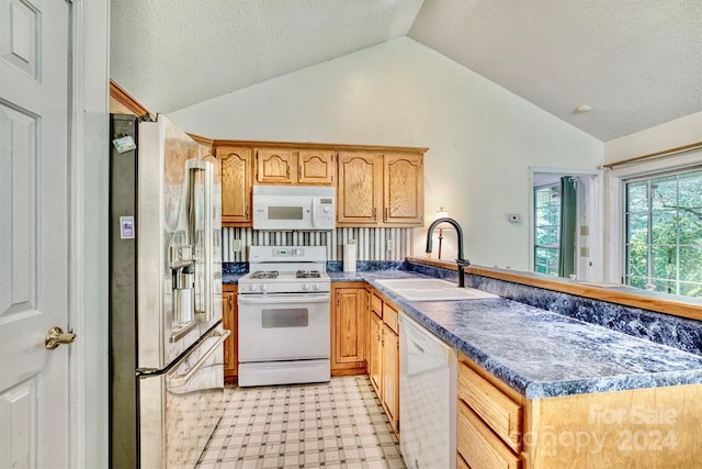 kitchen featuring a textured ceiling, white appliances, kitchen peninsula, sink, and lofted ceiling