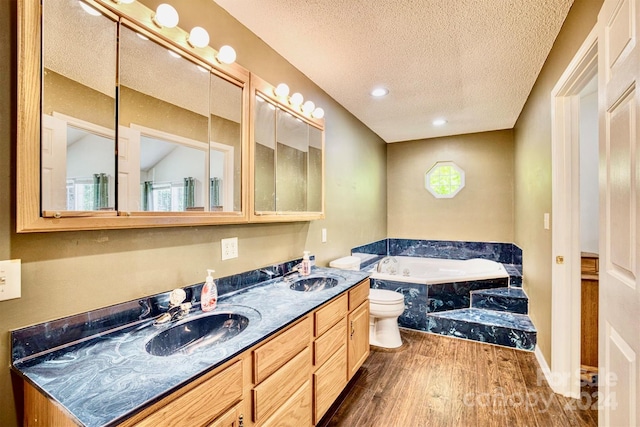 bathroom with tiled tub, toilet, vanity, a textured ceiling, and wood-type flooring