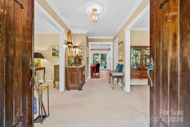 foyer entrance featuring light carpet and ornamental molding