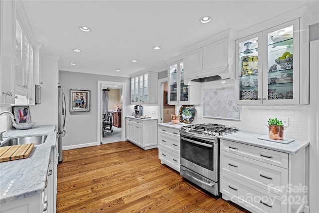 kitchen featuring tasteful backsplash, light hardwood / wood-style flooring, stainless steel appliances, sink, and white cabinets