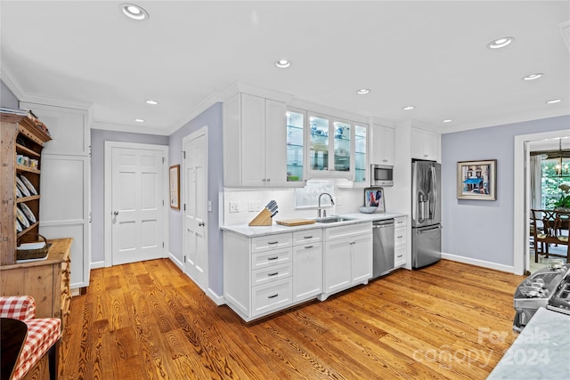 kitchen with light wood-type flooring, stainless steel appliances, white cabinetry, sink, and tasteful backsplash