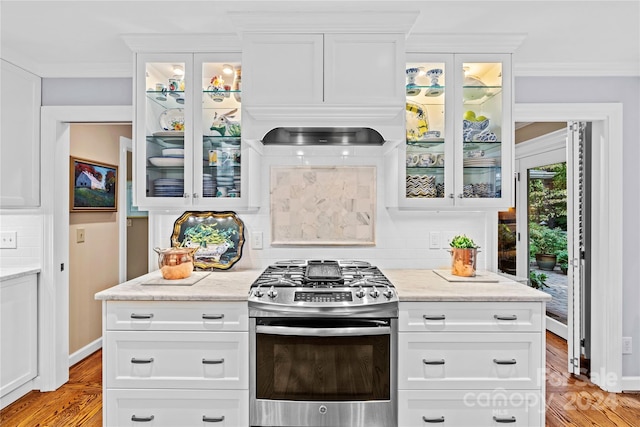 kitchen with ornamental molding, stainless steel range with gas cooktop, backsplash, and light hardwood / wood-style floors