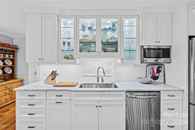 kitchen with backsplash, stainless steel appliances, white cabinetry, and sink