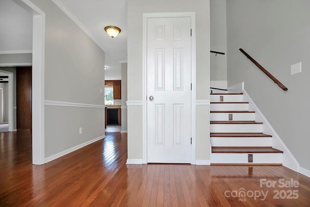 staircase with ornamental molding, wood-type flooring, and baseboards