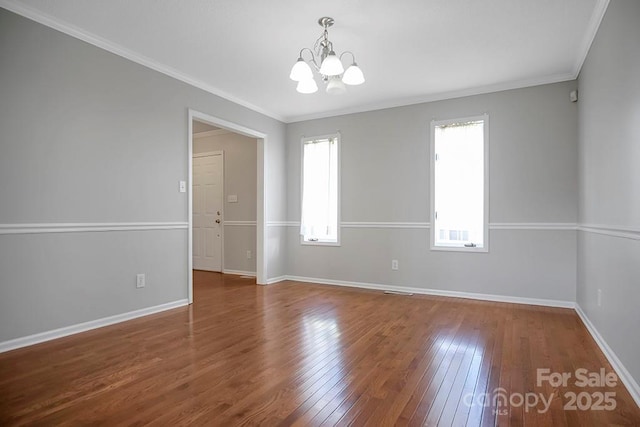 unfurnished room with baseboards, ornamental molding, wood-type flooring, and an inviting chandelier