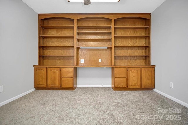 interior space with light carpet, baseboards, and built in desk