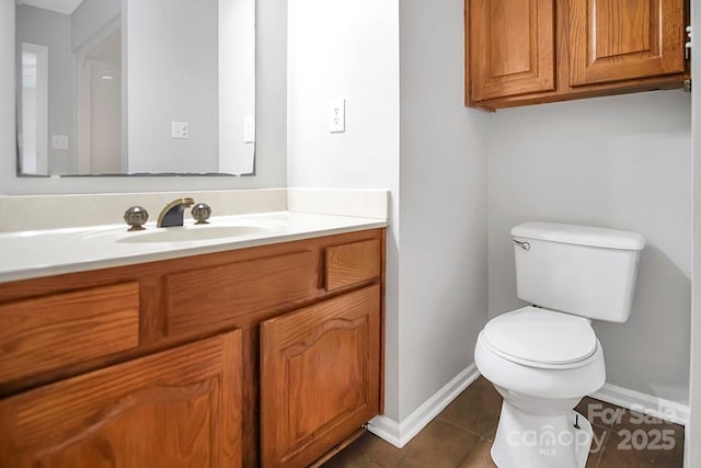 half bathroom with toilet, tile patterned flooring, baseboards, and vanity