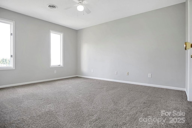 carpeted spare room featuring visible vents, baseboards, and a ceiling fan