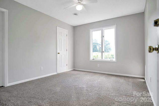 empty room with carpet floors, visible vents, ceiling fan, and baseboards