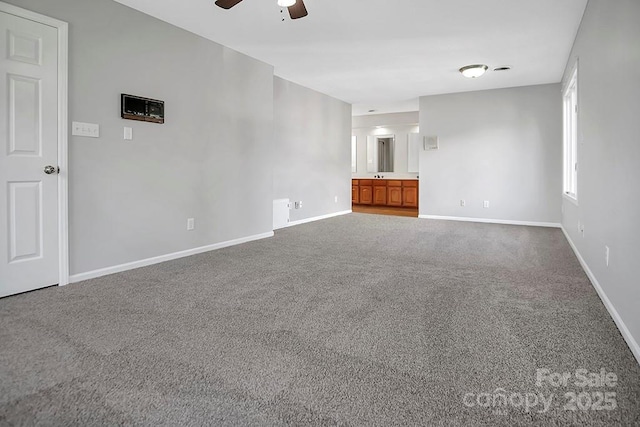 unfurnished room featuring a ceiling fan, dark carpet, and baseboards