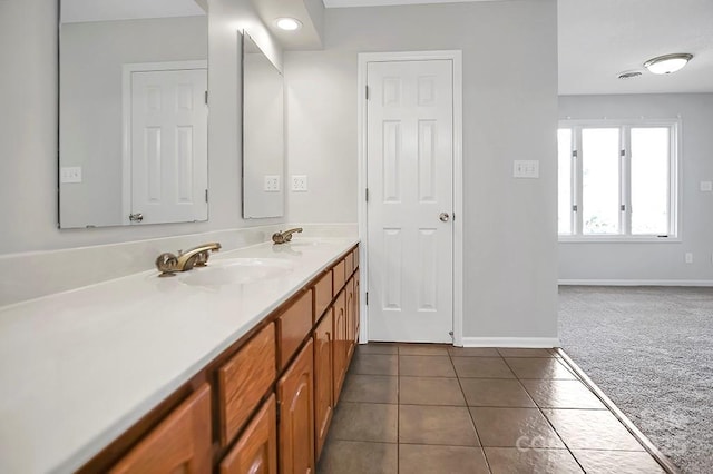 bathroom with double vanity, baseboards, a sink, and tile patterned floors