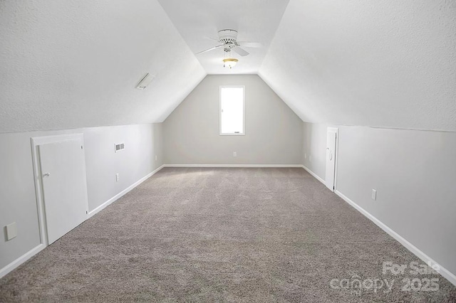 bonus room featuring lofted ceiling, baseboards, a textured ceiling, and carpet flooring