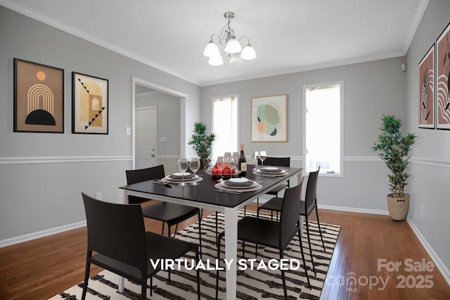 dining space with a chandelier, ornamental molding, wood finished floors, and baseboards