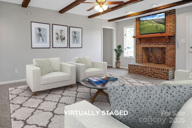 living room with baseboards, ceiling fan, carpet flooring, a brick fireplace, and beam ceiling