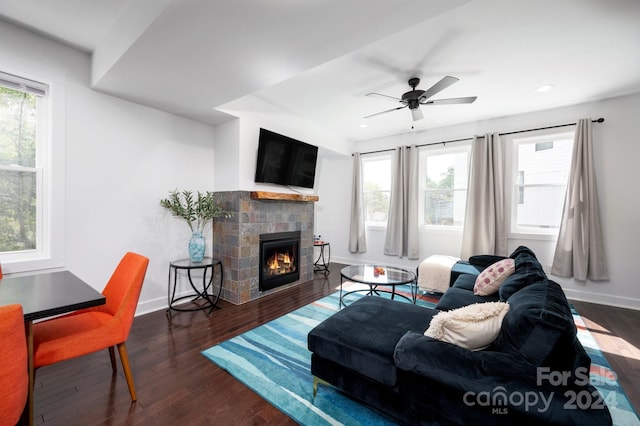 living room with a tile fireplace, dark hardwood / wood-style flooring, ceiling fan, and plenty of natural light