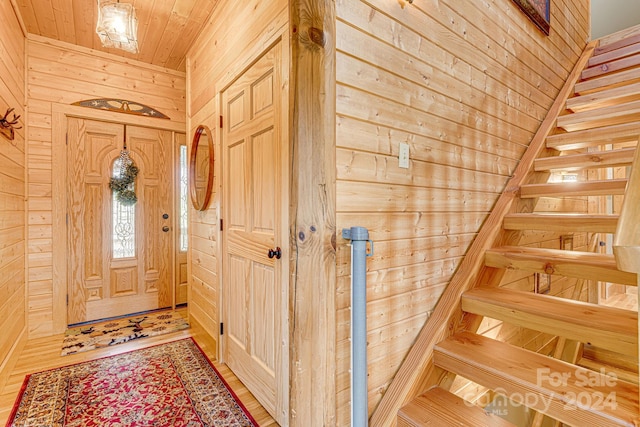 foyer with wood ceiling, light hardwood / wood-style flooring, and wood walls