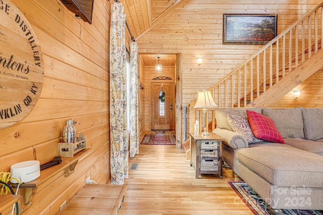 living room featuring light wood-type flooring, wood ceiling, vaulted ceiling, and wood walls