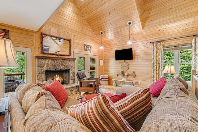 living room with a fireplace, hardwood / wood-style floors, french doors, high vaulted ceiling, and wooden walls