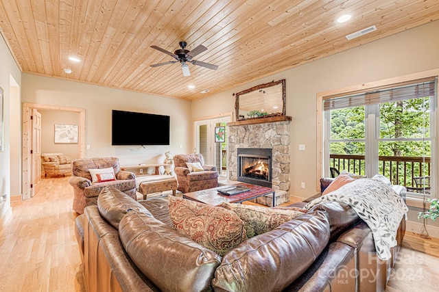 living room with light wood-type flooring, a stone fireplace, ceiling fan, and wooden ceiling