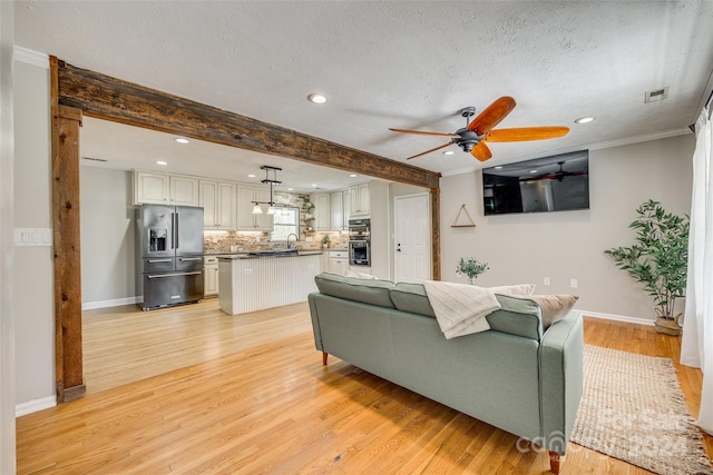 living room featuring light hardwood / wood-style floors, ornamental molding, beamed ceiling, and ceiling fan