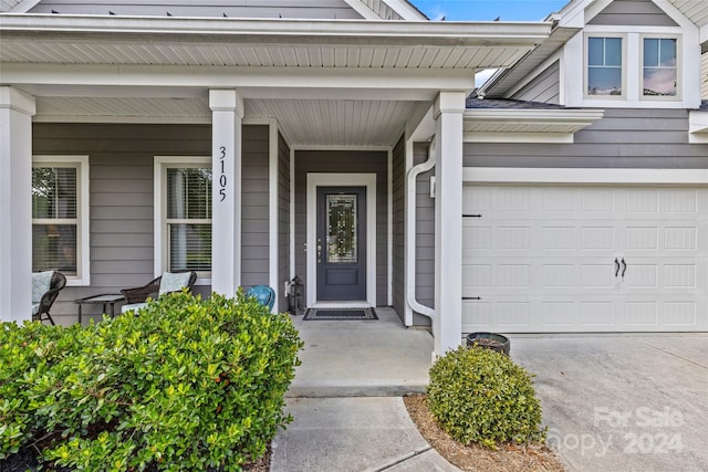 doorway to property with covered porch and a garage