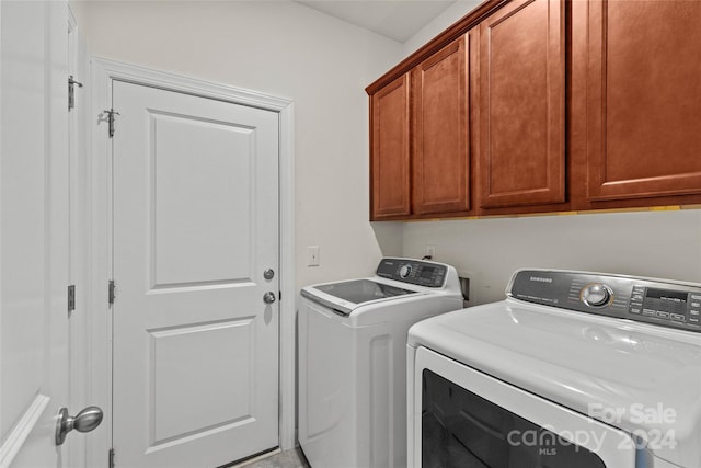 laundry room featuring separate washer and dryer and cabinets