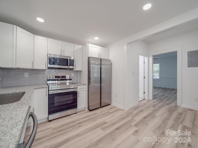 kitchen featuring appliances with stainless steel finishes, sink, light wood-type flooring, and tasteful backsplash