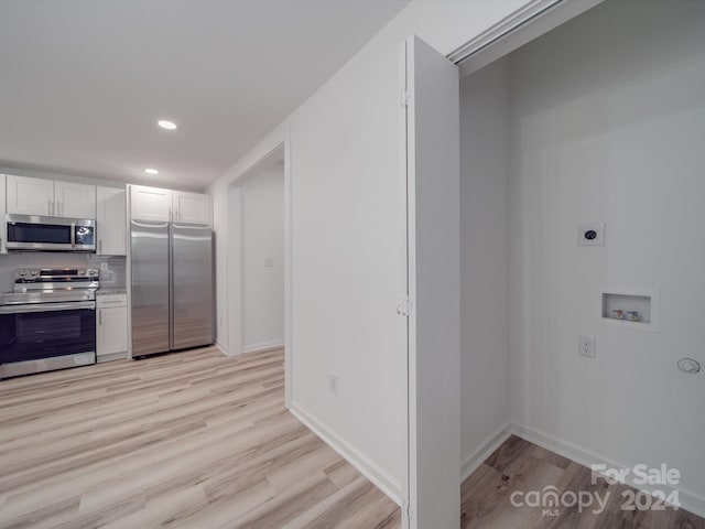 kitchen with light wood finished floors, appliances with stainless steel finishes, white cabinetry, and recessed lighting