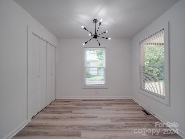 interior space featuring visible vents, a notable chandelier, light wood-style flooring, and baseboards