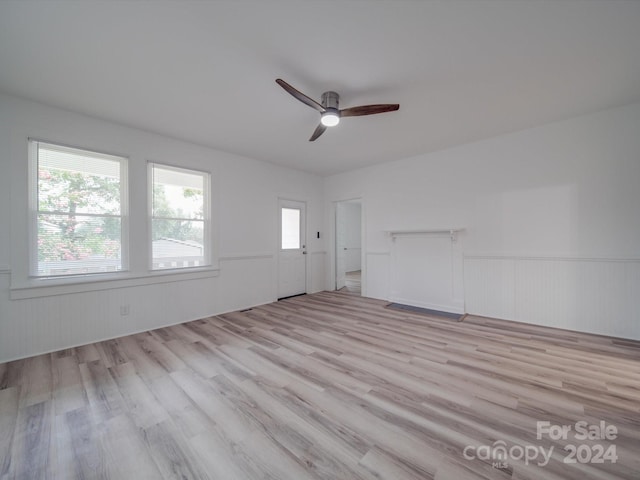 unfurnished living room featuring wainscoting, wood finished floors, and a ceiling fan