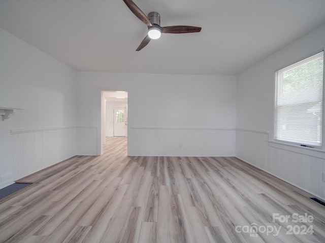 spare room with a wainscoted wall, wood finished floors, and a ceiling fan