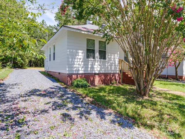 view of home's exterior with crawl space, driveway, and a lawn