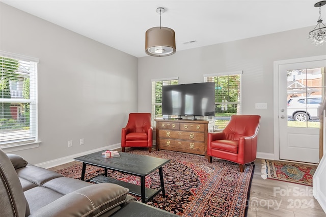 living room featuring plenty of natural light, wood-type flooring, and an inviting chandelier