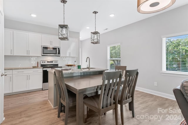 dining space featuring a healthy amount of sunlight, sink, and light hardwood / wood-style flooring