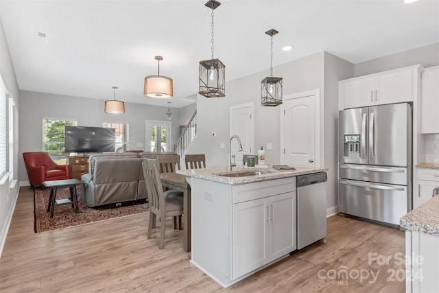 kitchen featuring light hardwood / wood-style flooring, appliances with stainless steel finishes, a kitchen island with sink, sink, and white cabinets